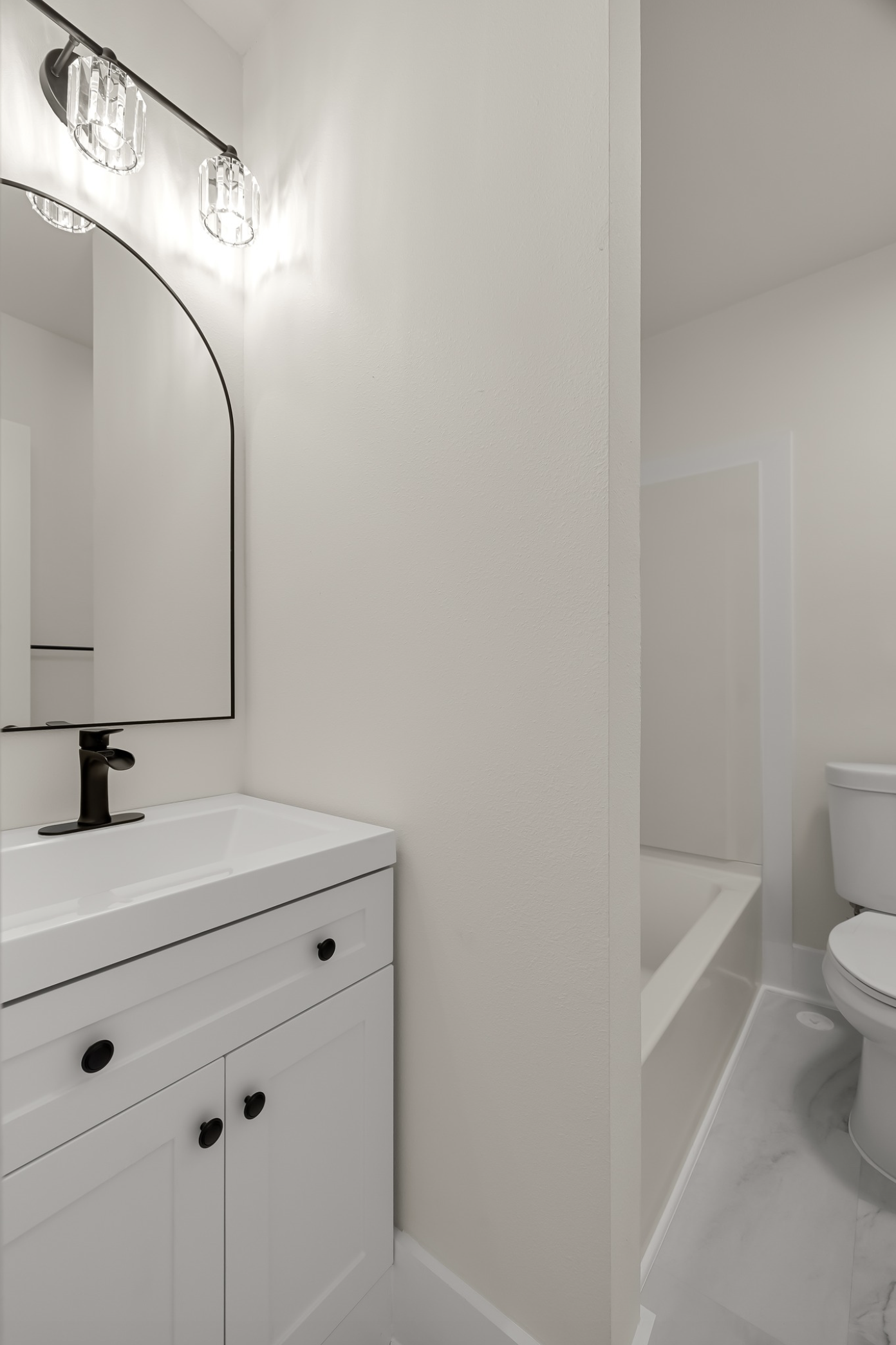 Mayflower Apartments — bath with arched mirror and brass-and-black fixtures